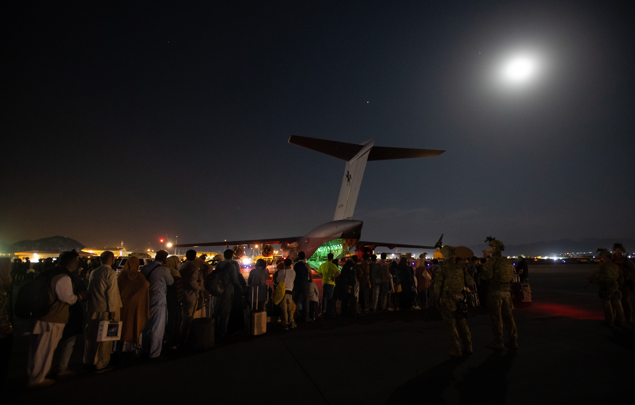 Evacuees board C-17A A41-208 as Australian Army Infantry personnel provide security in Kabul